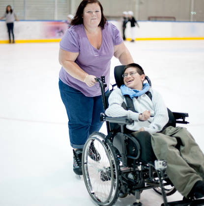 Young Man Ice Skating, being pushed in his Wheelchair by his Support Worker.